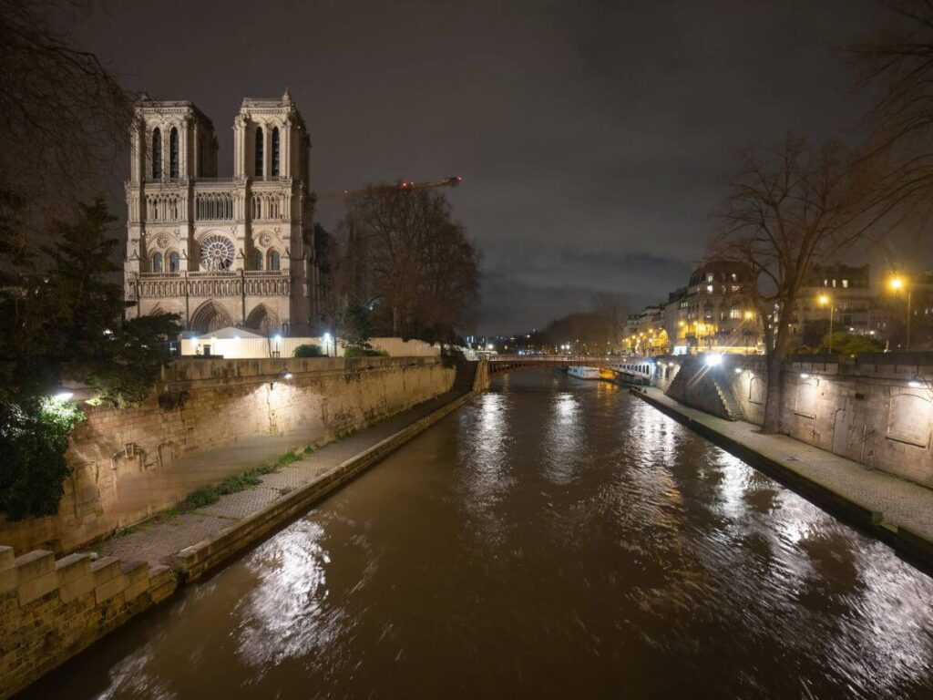 The Notre Dame at night with a view of the river and some lights