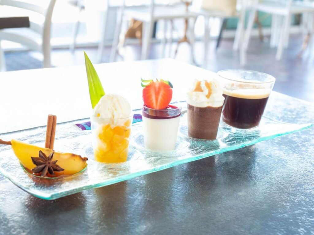 A glass dish with four mini desserts and an espresso on it served as a Cafe Gourmand in France