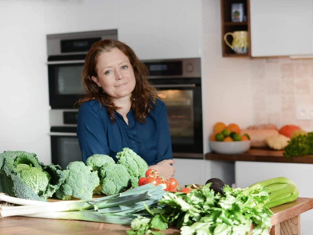 Woman stood in a kitchen with fresh vegetables to cook