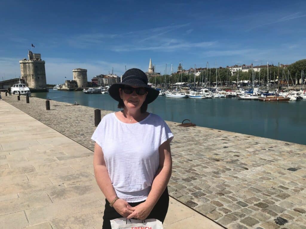Lady in a hat stood by the water having her photo taken