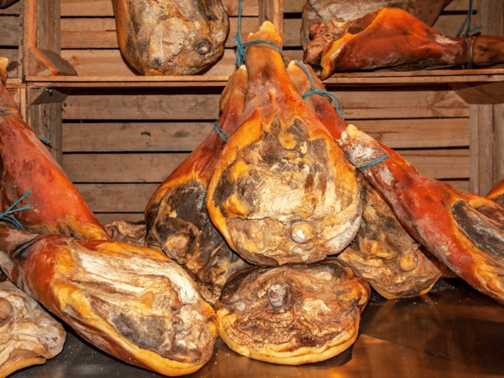 Joints of ham sat on a wooden shelf