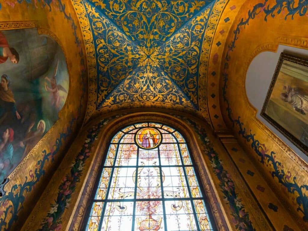 An ornate church ceiling with a stained glass window