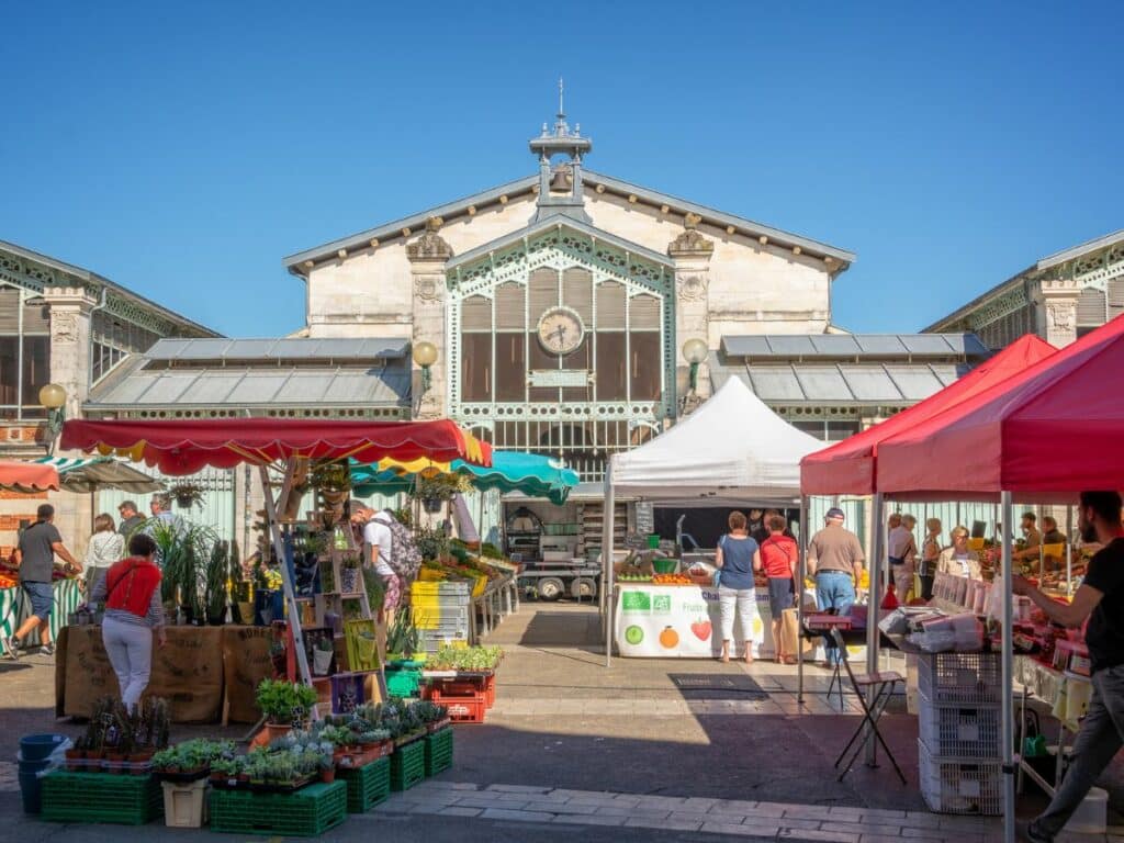 Market stalls outside a large stone building with people shopping