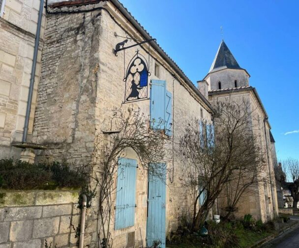 An old building behind a church with a hanging sign