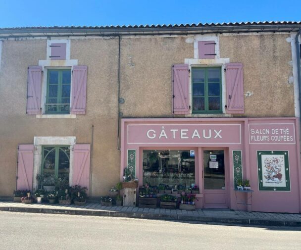 Old stone building with a pink facade and flowers outside