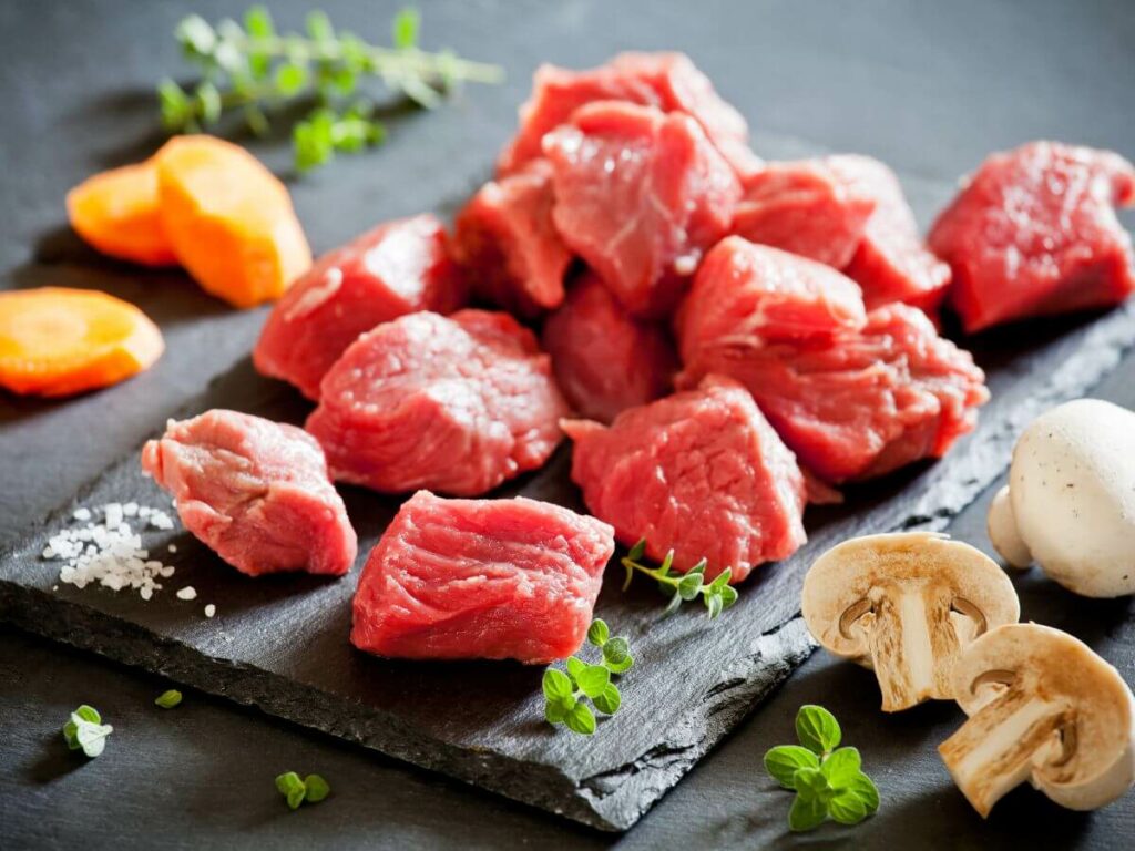 Diced beef on a slate with carrots and mushrooms around it