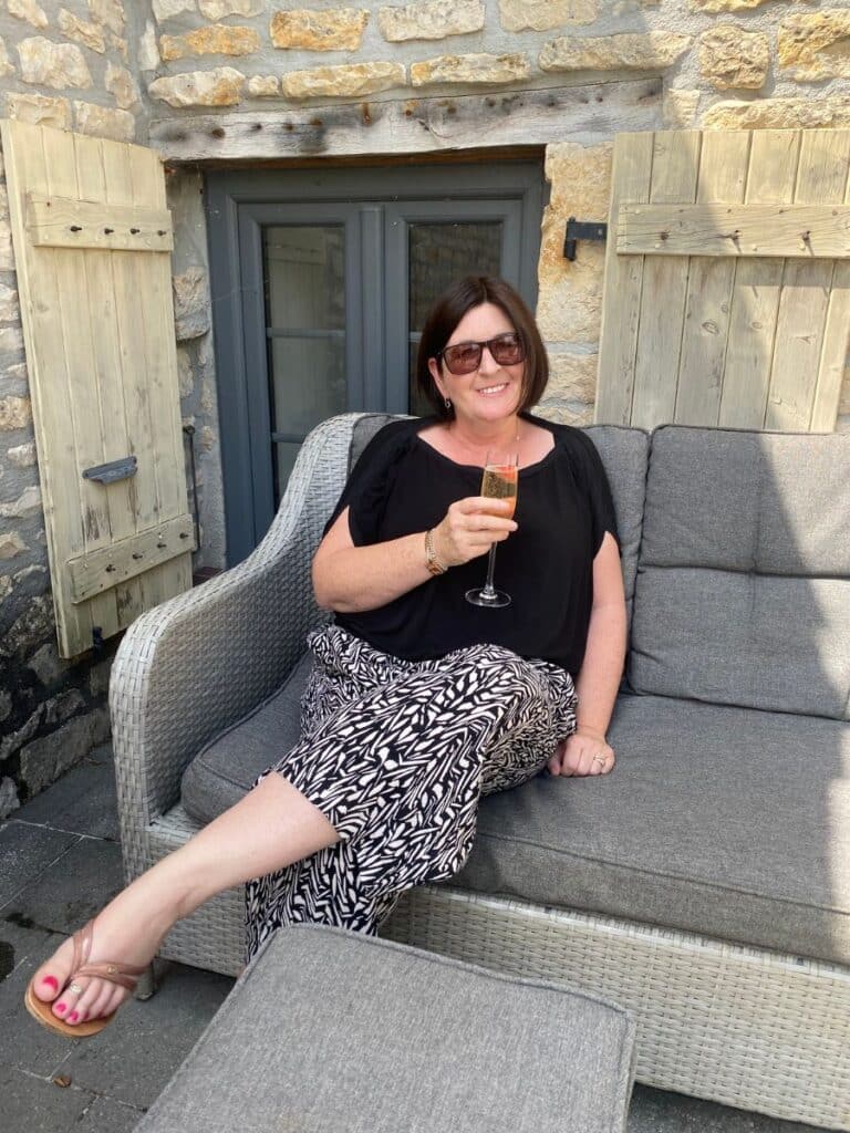A woman sitting on a sofa outside drinking a glass of wine
