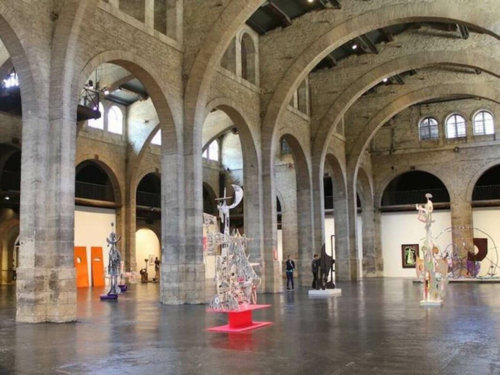 The inside of a building with lots of big arches and art with a shiny floo in a museum in Bordeaux