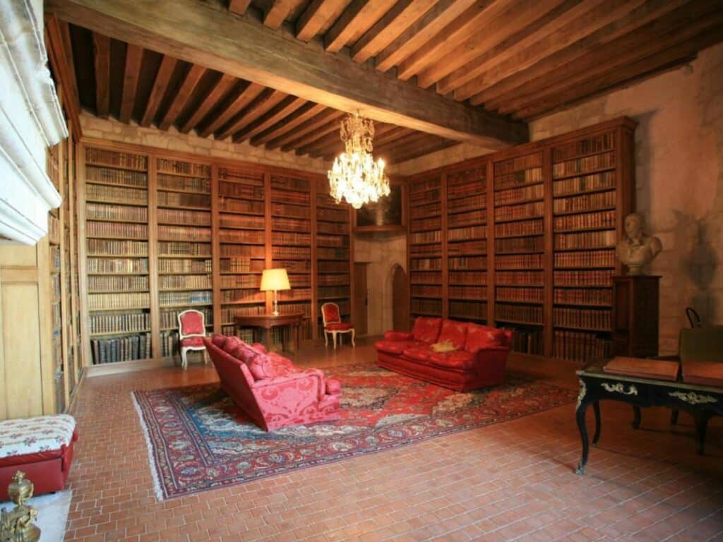 Two red sofaos and shelves with a rug in the salon at the Chateau of Rochefoucauld