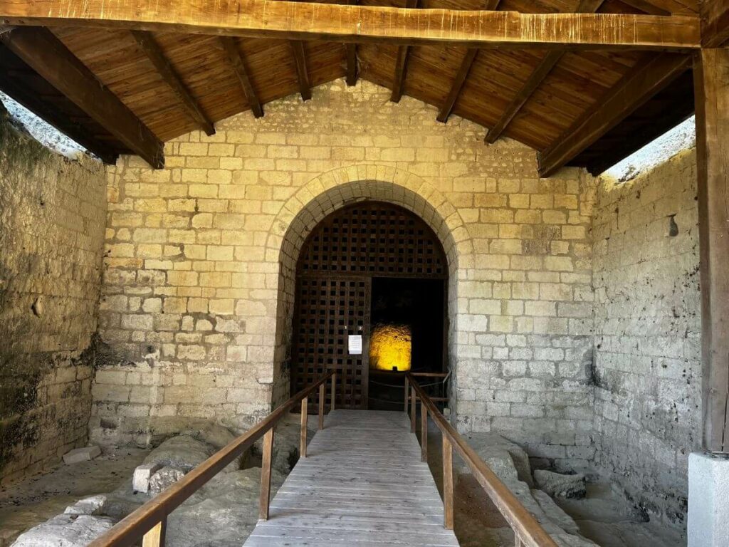 A stone archway and wooden bridge leading to a church in Aubeterre-sur-Dronne