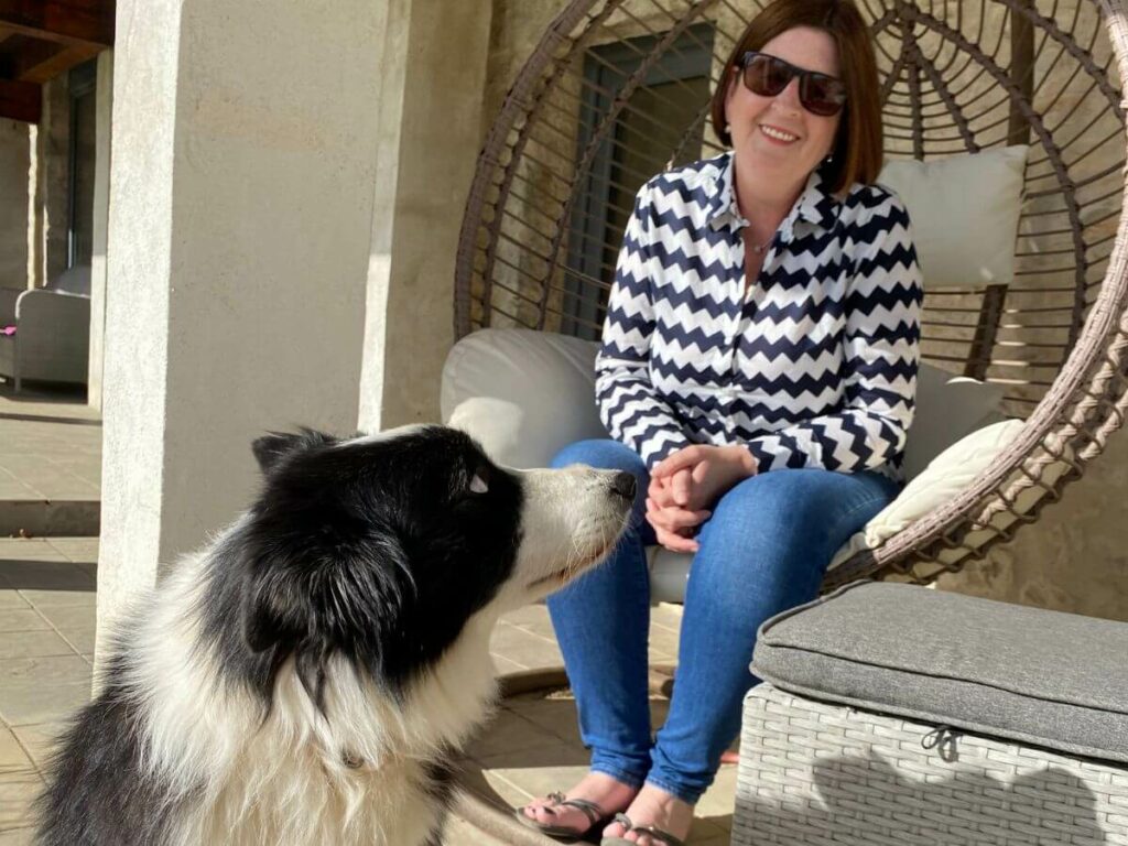 A woman in a swing chair with a black and white dog