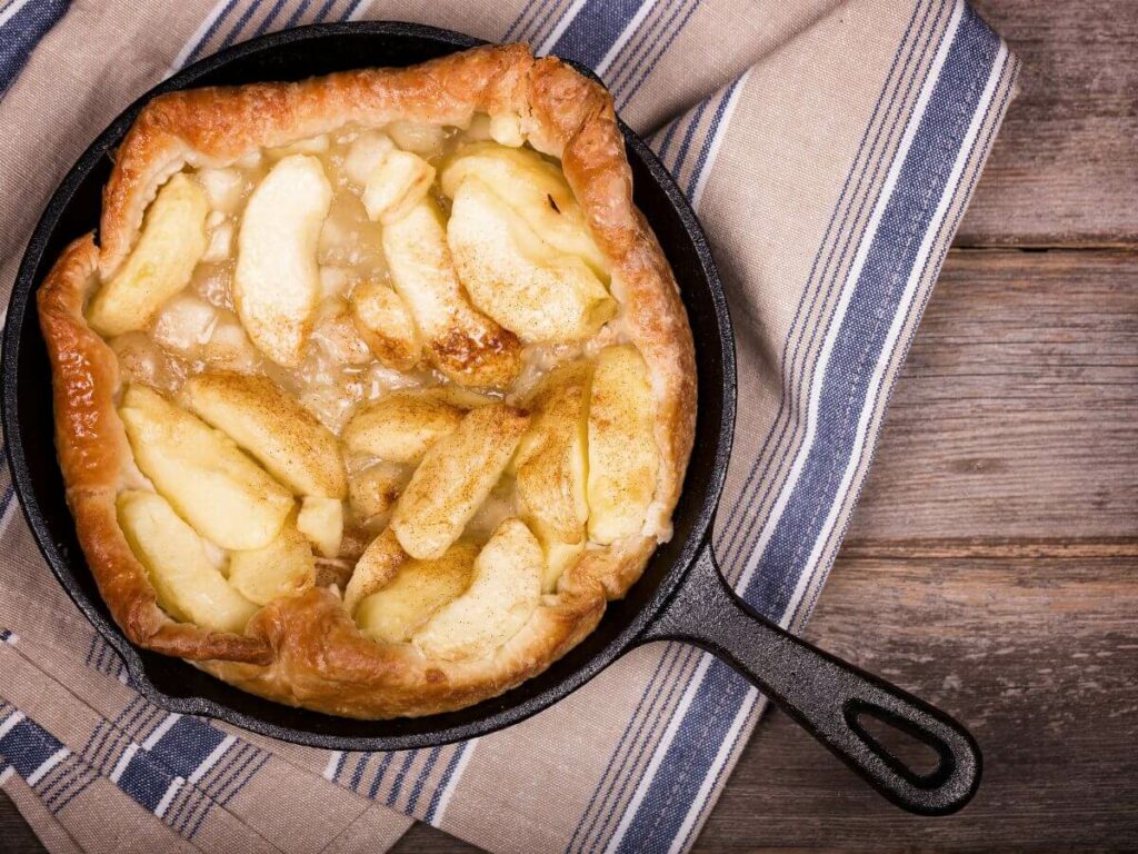 An apple tarte tatin in an ovenproof pan sat on a tea towel