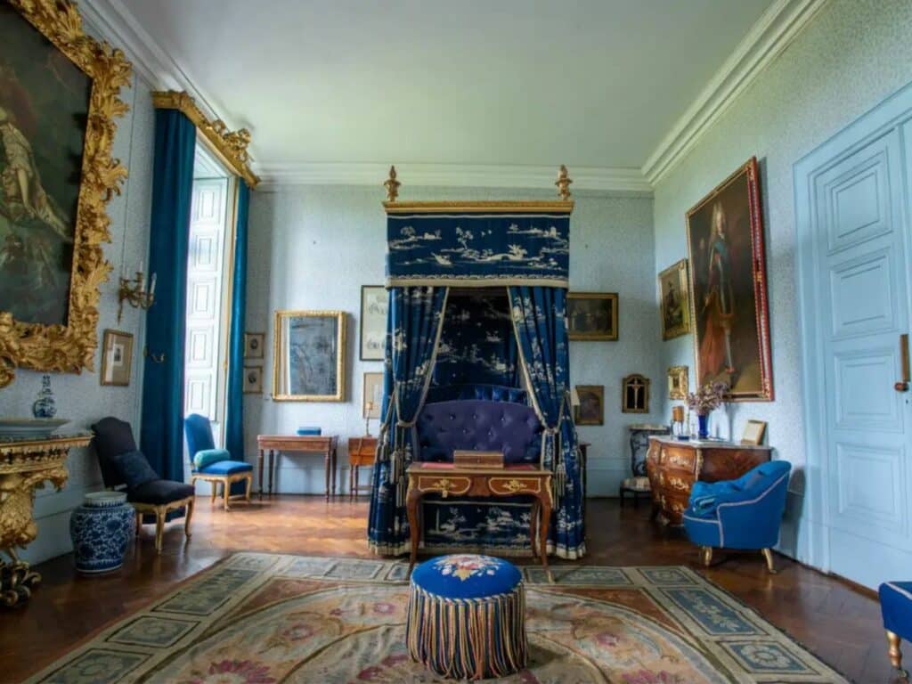 A royal blue bedroom at the Chateau of Vertueil with four poster bed