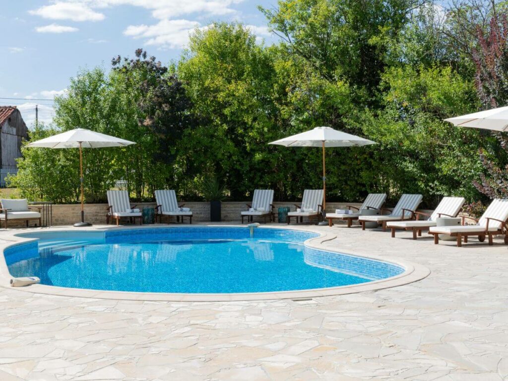 An inground pool with a terrace and sunbeds at a gite in the Charente in France