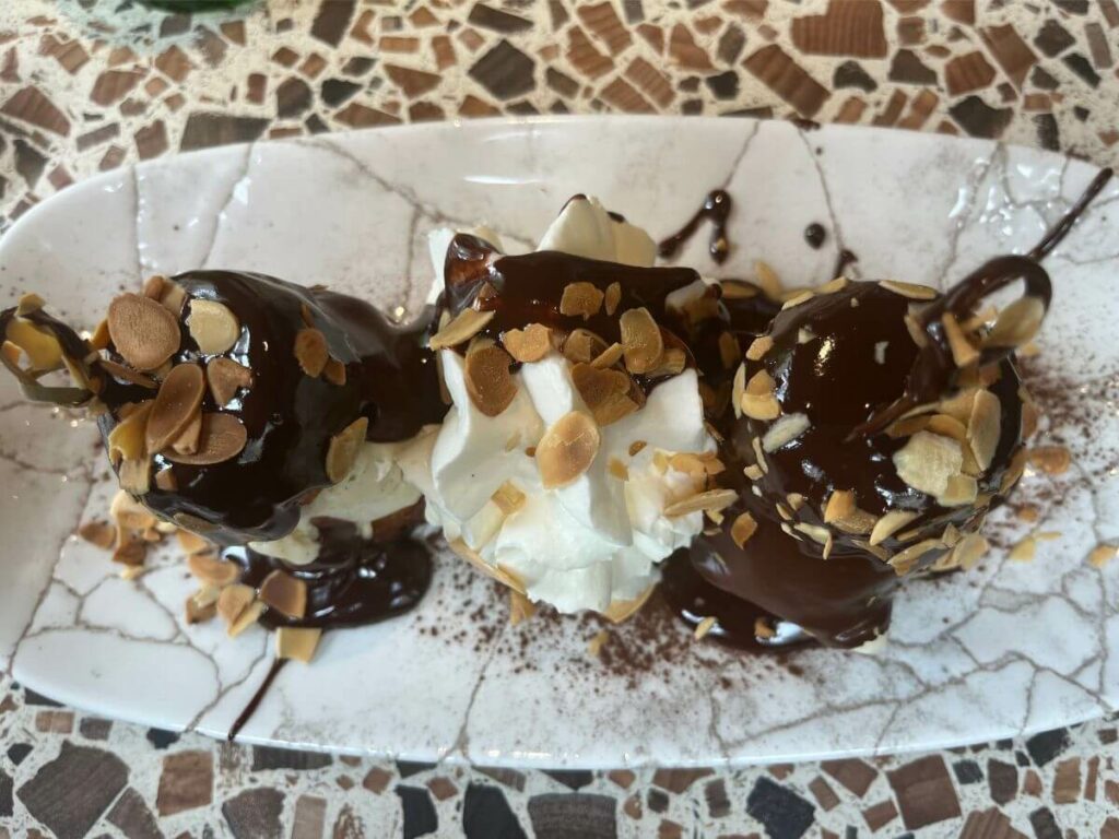A plate with profiteroles with icecream and chocolate