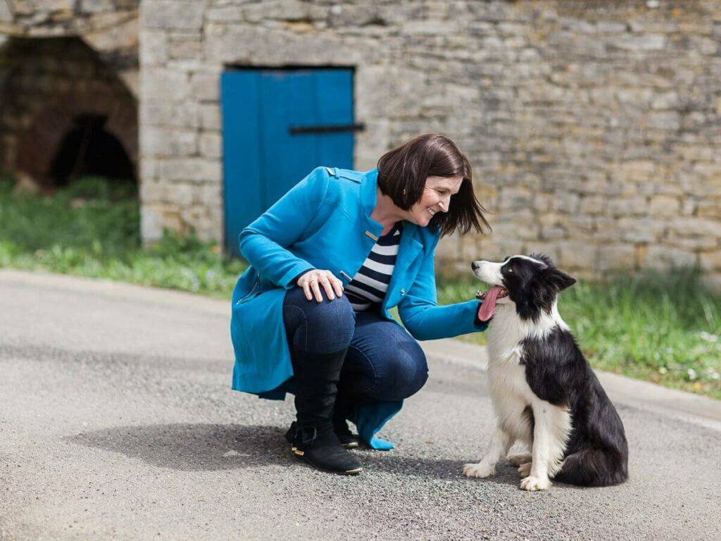 A border collie with a lady outside an old stone building in the Charente in France