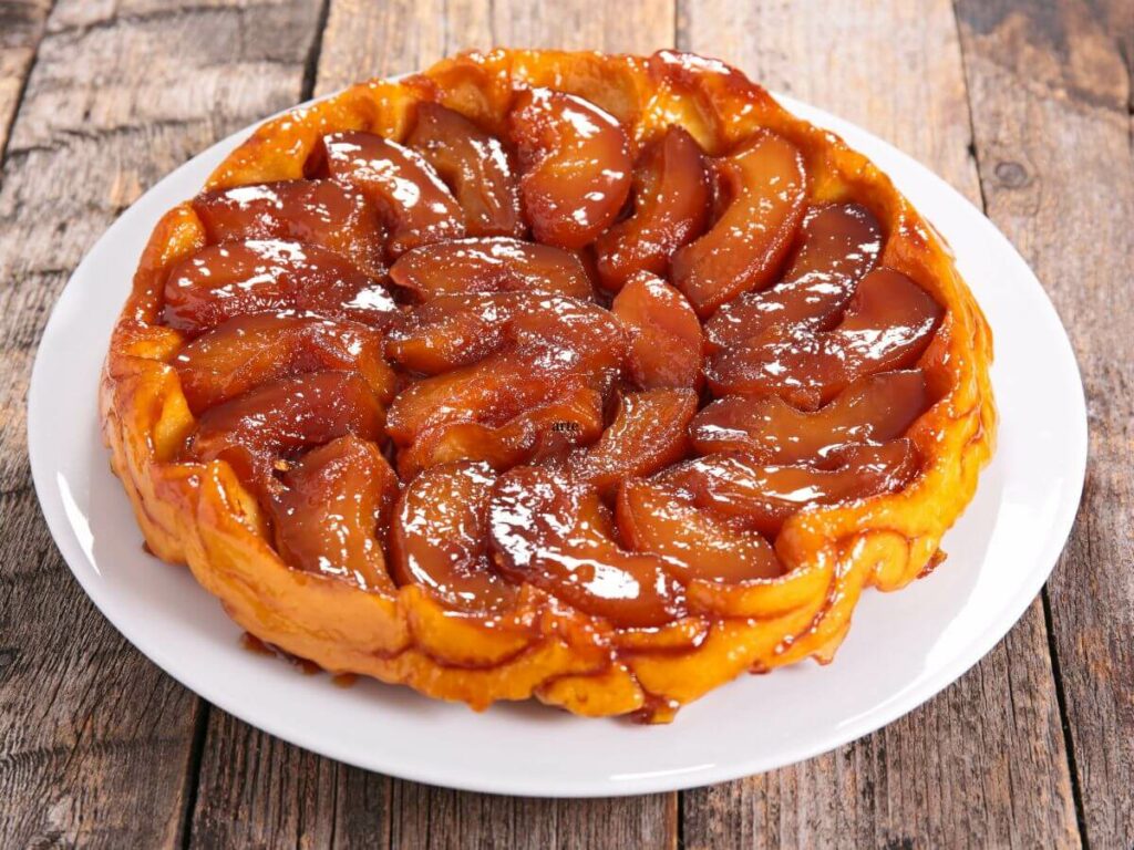 A plate with an apple French dessert telling the story of tarte tatin history