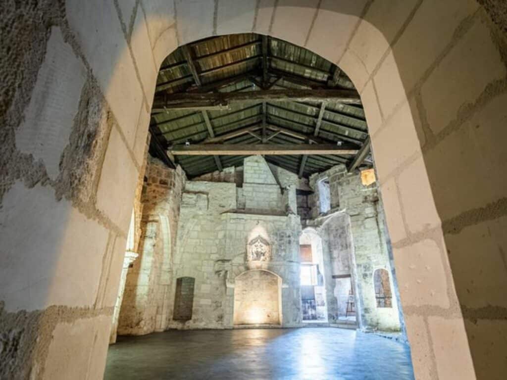 An arched room with a vaulted ceiling and big fireplace with flags hanging up in the chateau of Cognac