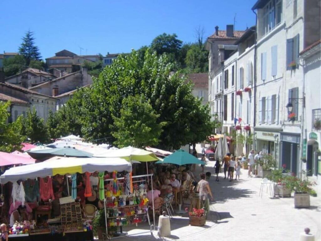 A busy market square at Aubeterre-sur-Dronne with market stalls set up