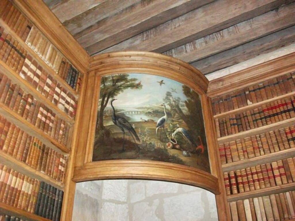 Shelves of books with an old painting in the Chateau de Rochefoucauld