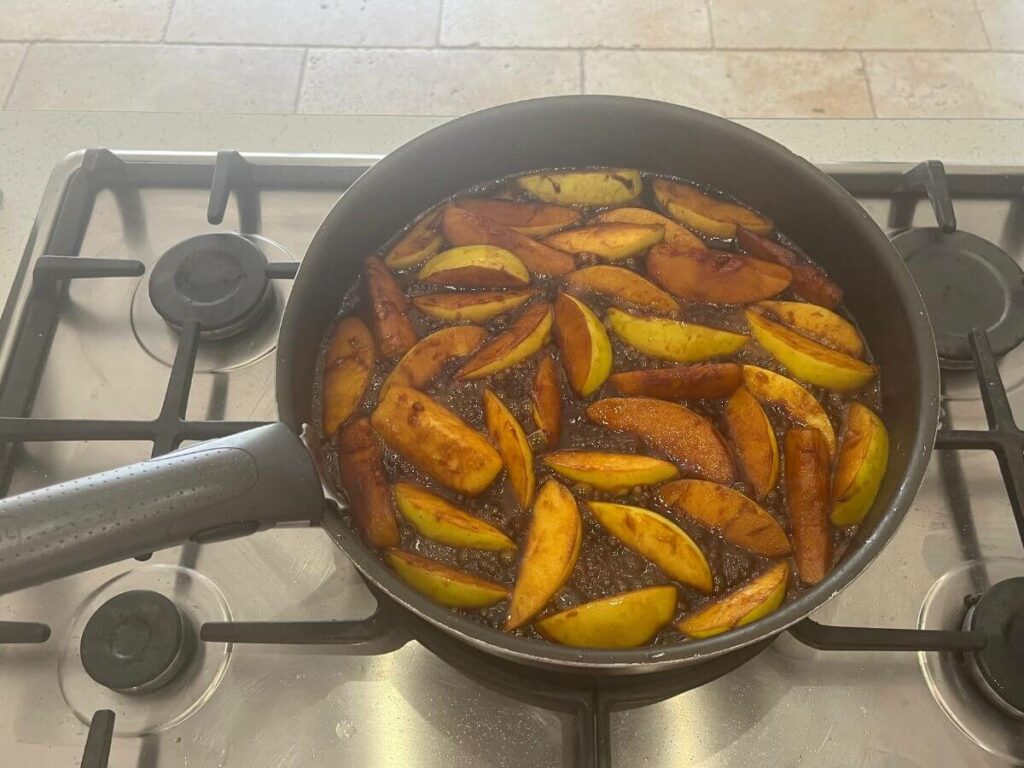 A pan on a gas hob caramelising apples