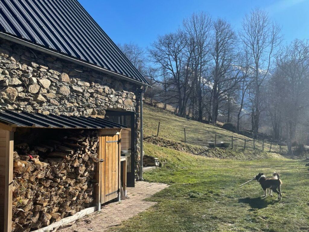A large woodshed filled with wood and blue sky in the background in the mountains in France
