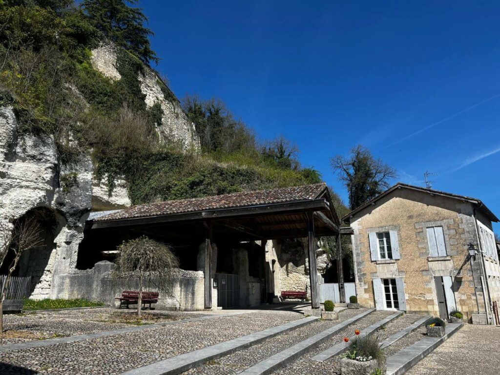 A big cliff with a building at the bottom in Aubeterre-sur-Dronne