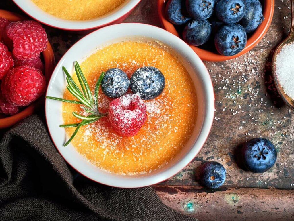 A creme brulee France with blueberries and raspberries sat on a wooden table