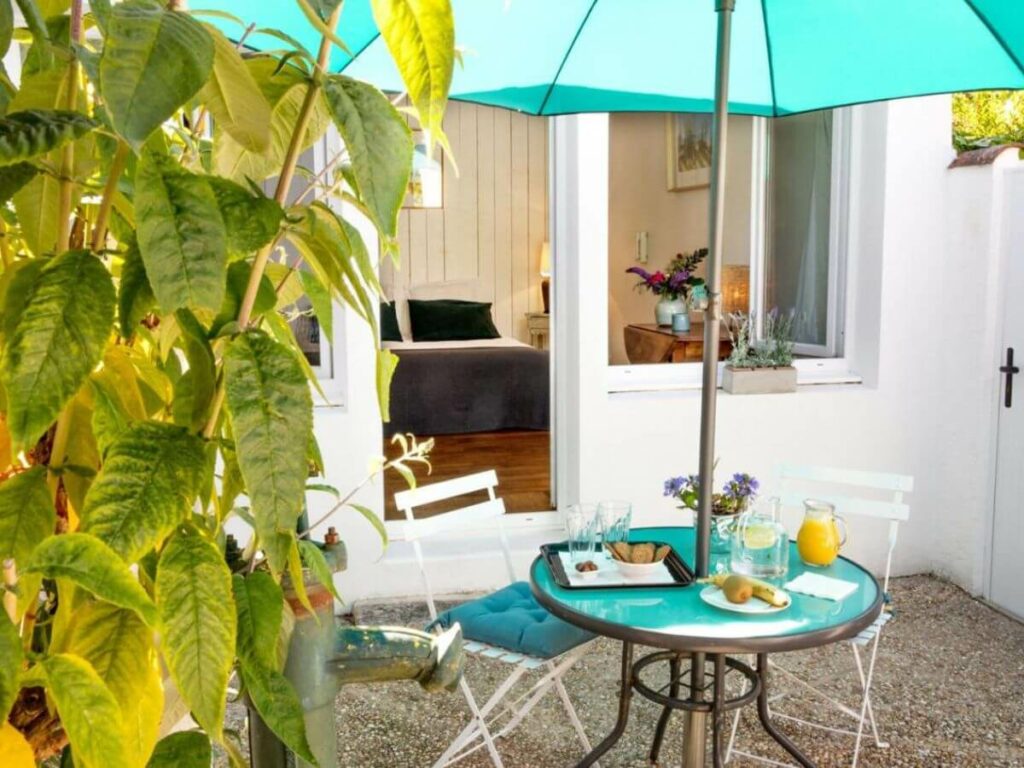 An outdoor patio table set with an umbrella and two chairs at a bed and breakfast in La Rochelle