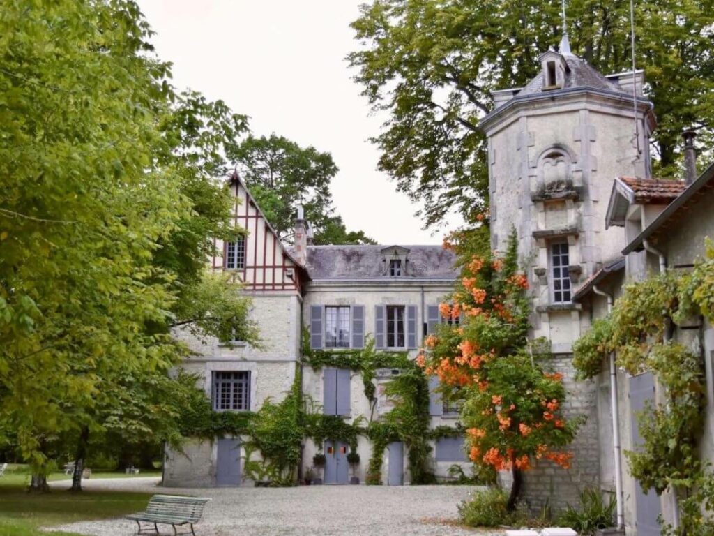 An old French building with a tower and trees at the front