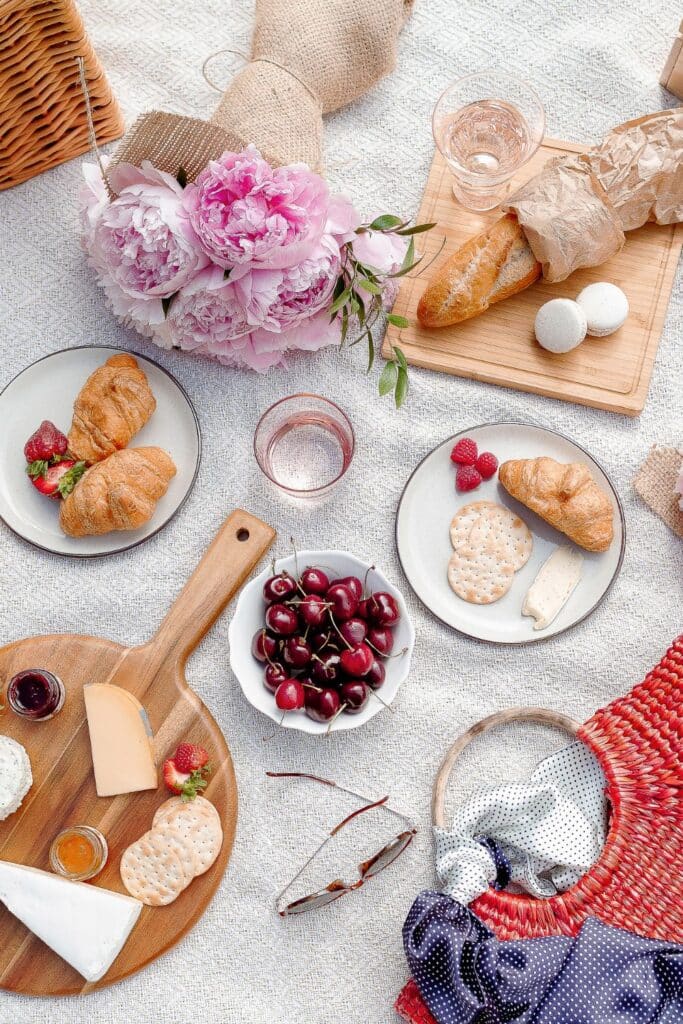 A chic Parisian picnic by the Seine with a woven basket filled with baguettes, a bottle of rosé, and vibrant yellow roses, set against a softly blurred Eiffel Tower in the background.