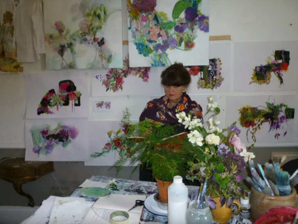 A woman painting flowers in an artist studio in France
