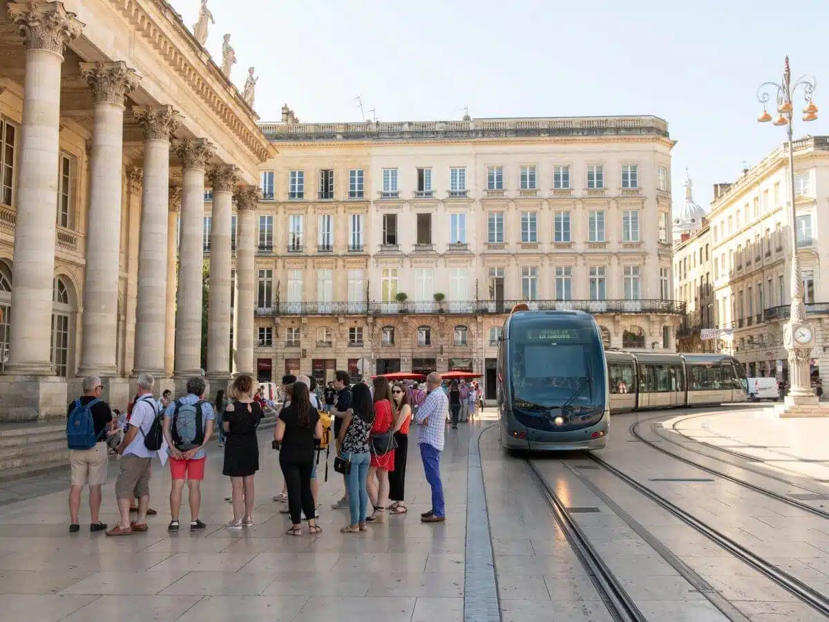 the main square in Bordeaux with a tram some people and the hotel de ville