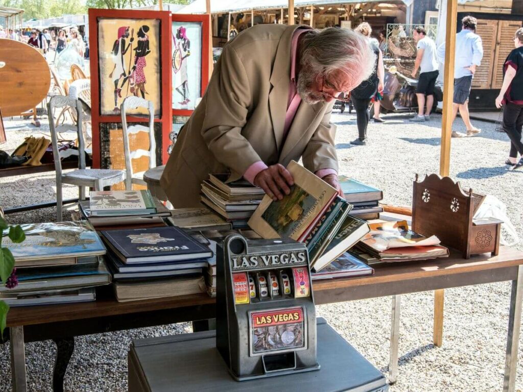 A man looking at books on a table in a market in Bordeaux outside