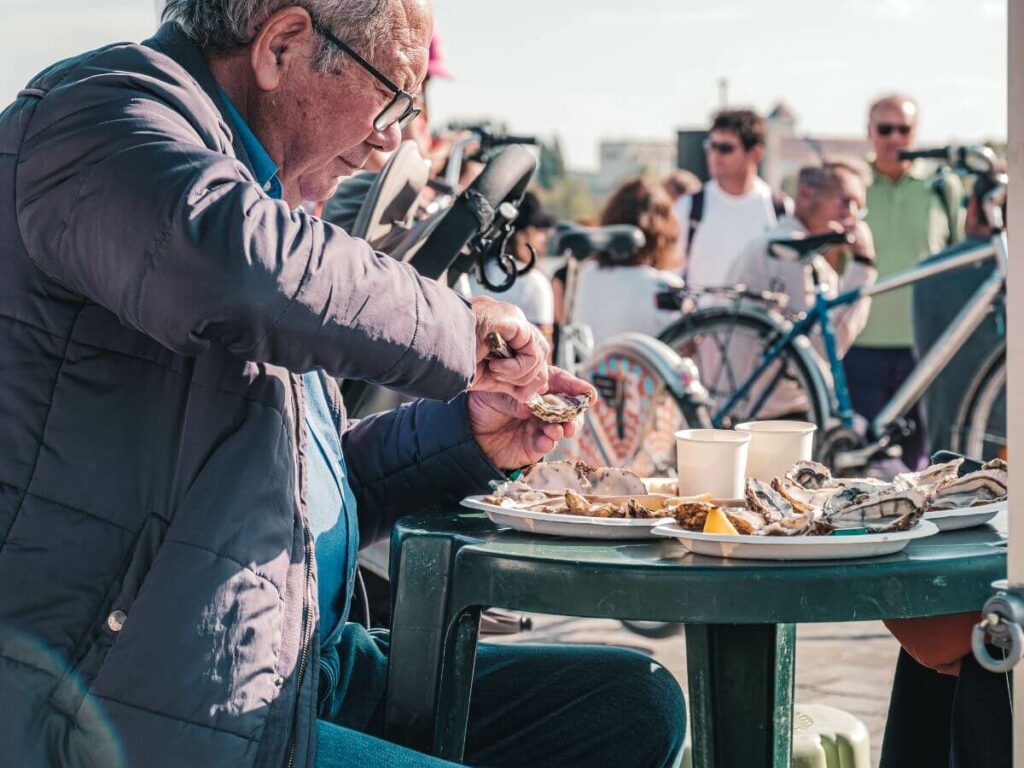 A man eating oysters at a table in a Bordeaux market
