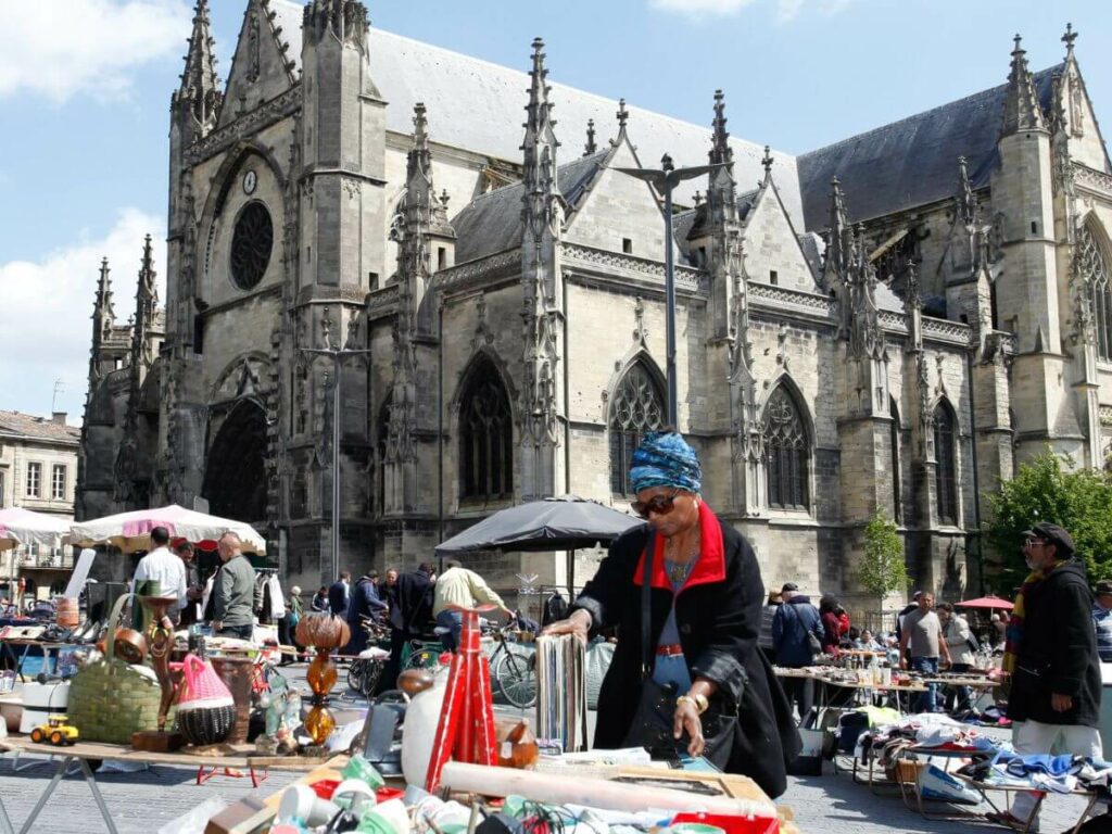 An outdoor flea market in Bordeaux city centre with a church in the background