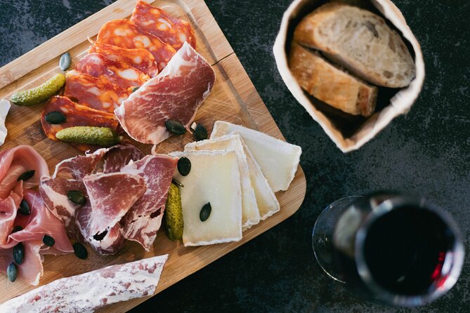 A selection of cured meat and cheese on a board with a glass of wine and some bread