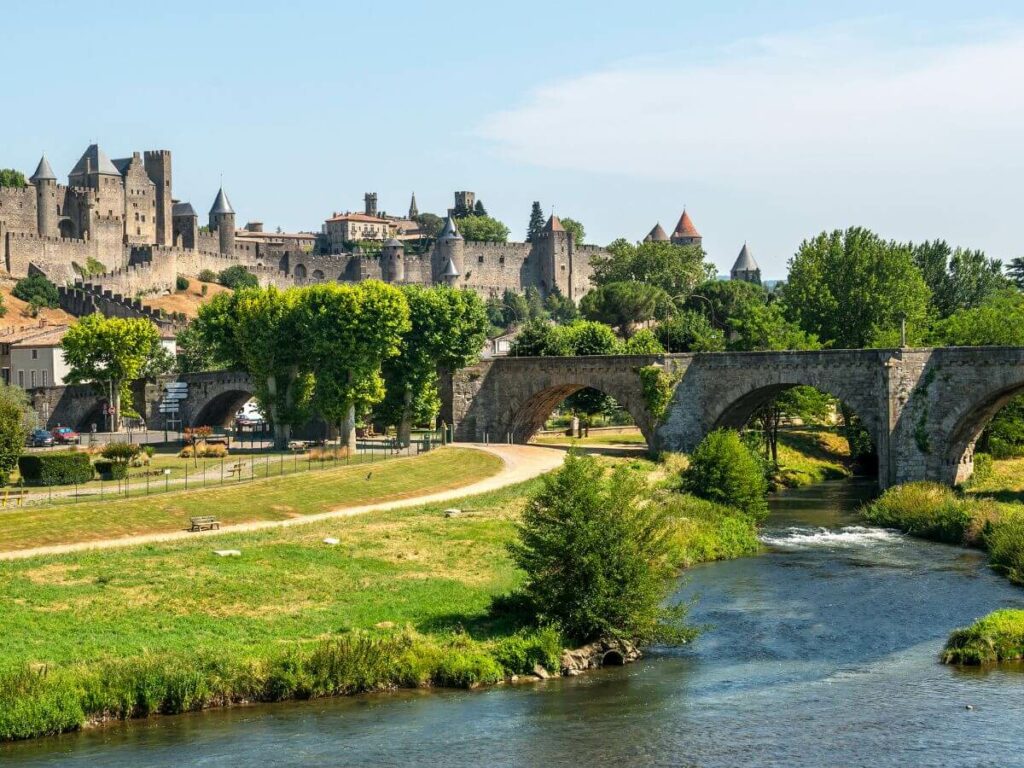 A view of Carcassone from across the river with grass in front of the city.