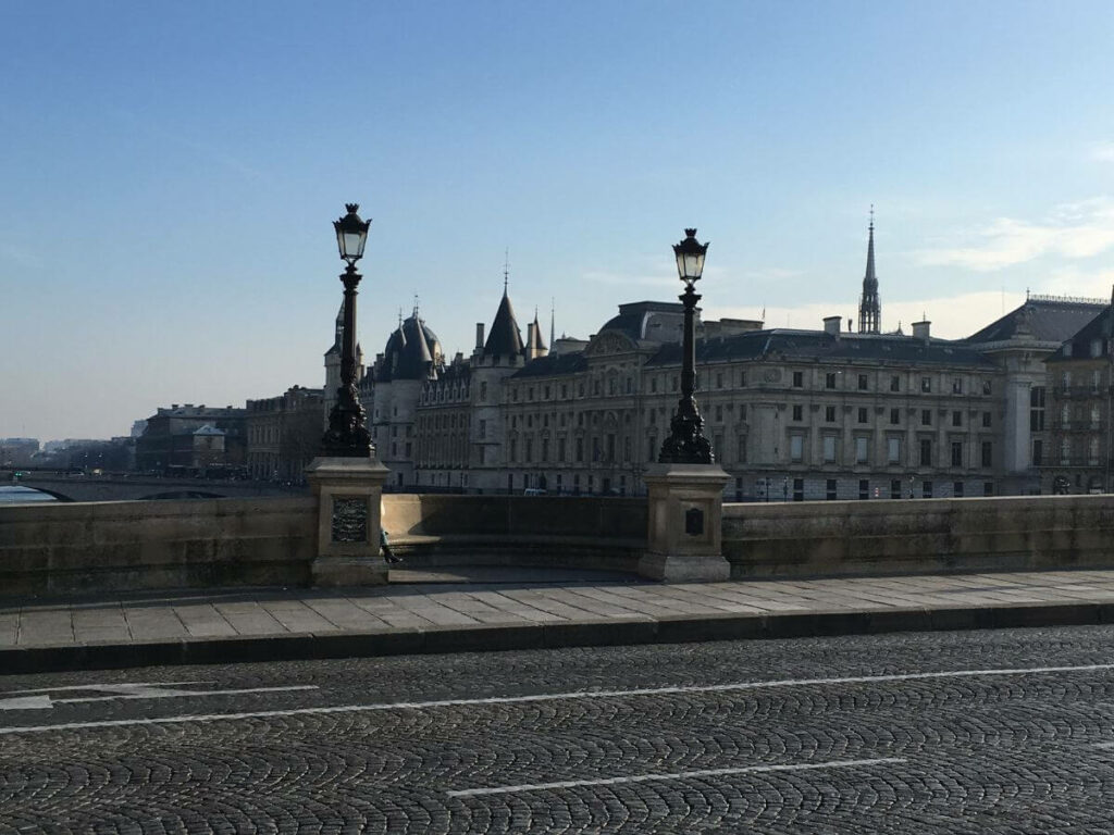 A bridge in Paris going over a river with buildings in the background