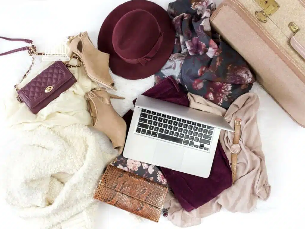 A collage picture of travel items including a laptop, hat, scarf, passport holder
