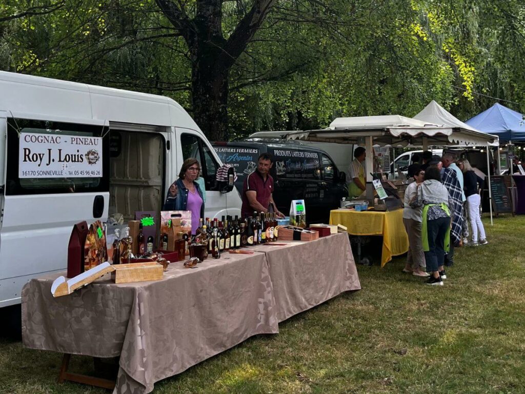 A table with a cloth and rows of bottles for sale in a field