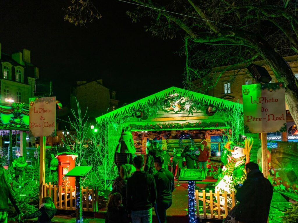 A Christmas market in France at night with a chalet lit up in bright green