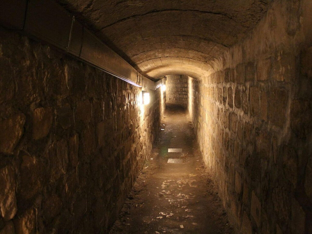A dimly lit underground tunnel running underneath Paris and into the catacombs