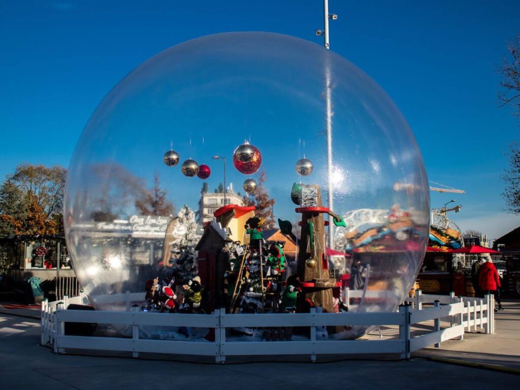 A see through snow globe with xmas decorations against a blue sky at the Reims Christmas Market