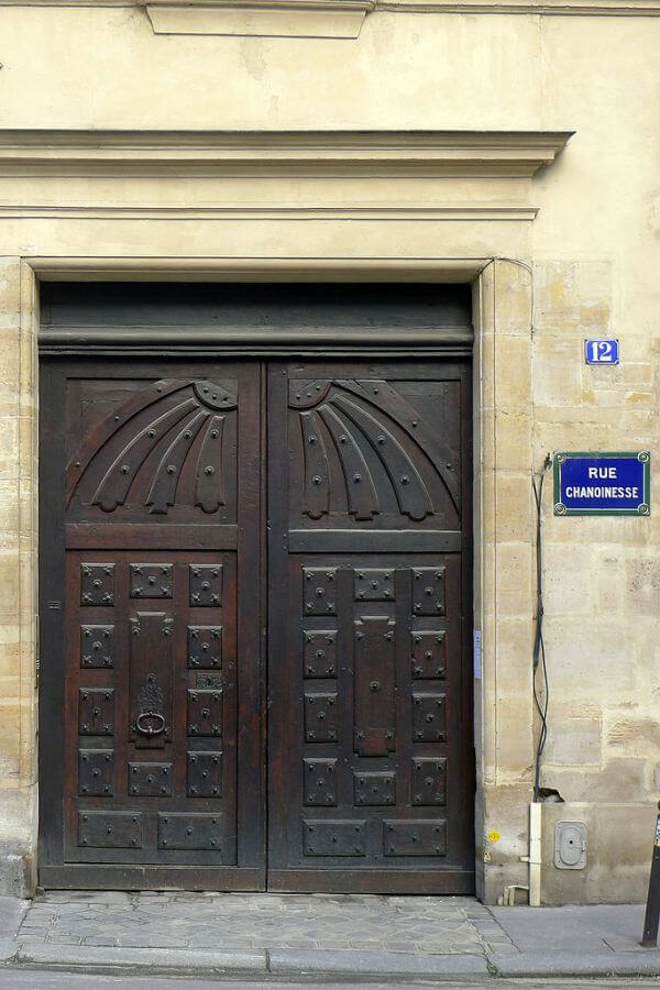 A double wooden front door set in a cream stone building in paris