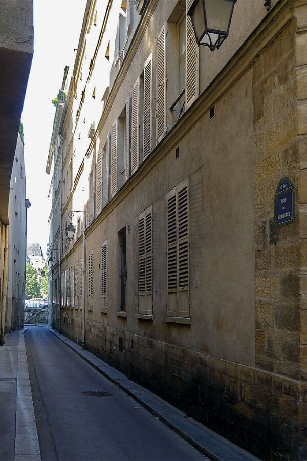 A deserted street in Paris with creams tone buildings on one side with dreary daylight come through