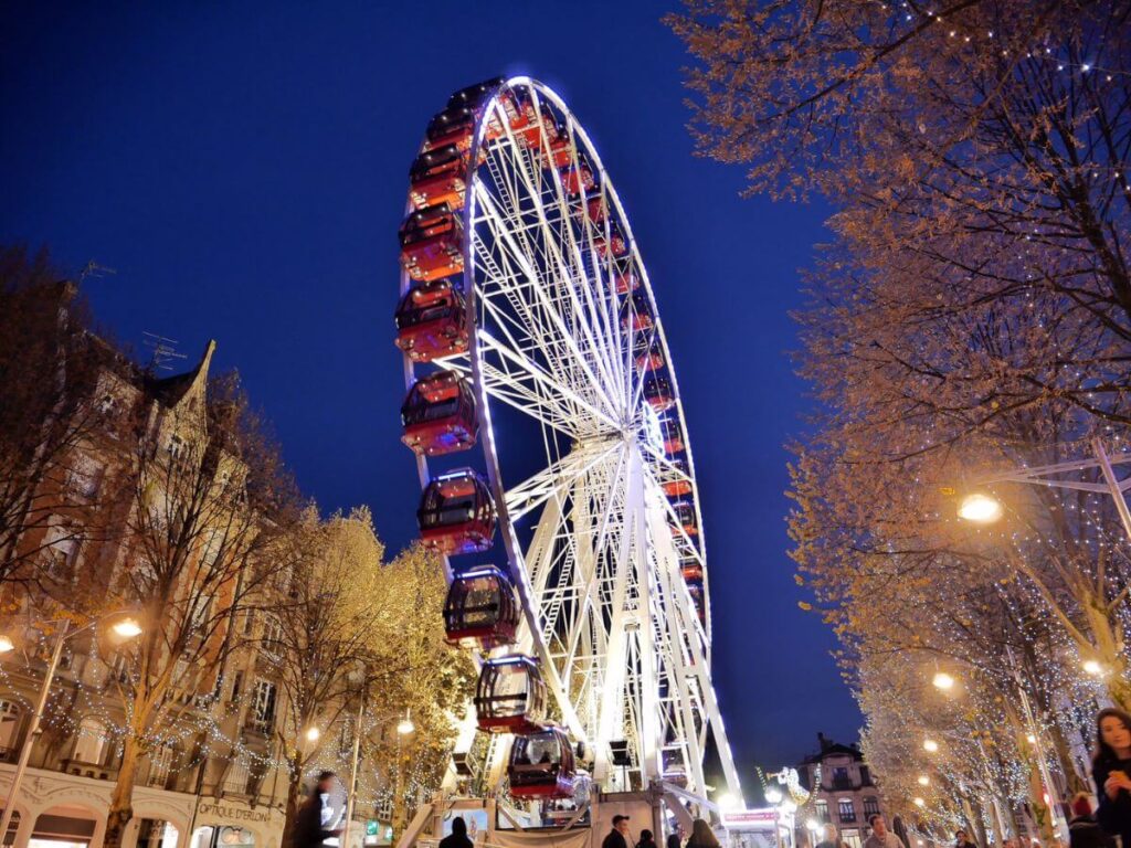A Ferris Wheel set against a night sky with a cathedral in the background in France in the winter