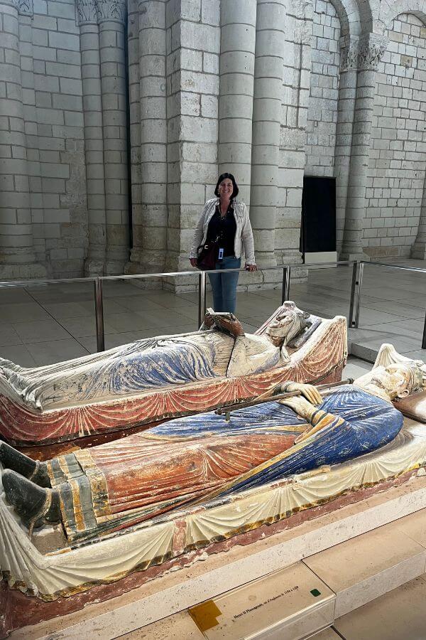 The effigy tombs of Eleanor of Aquitaine and Henry II laid in the Abbey Church at Fontevraud with a woman stood in the background