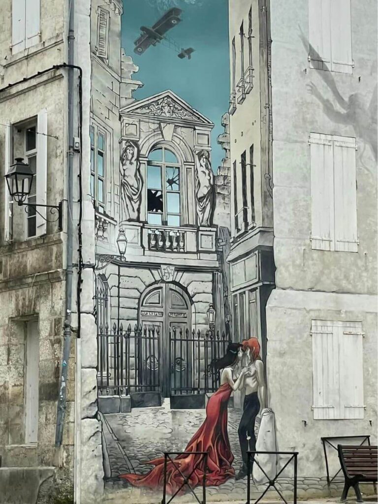 A huge cartoon wall mural in colour on an old building in the French town of Angouleme depicting a man and a woman with a plane going over
