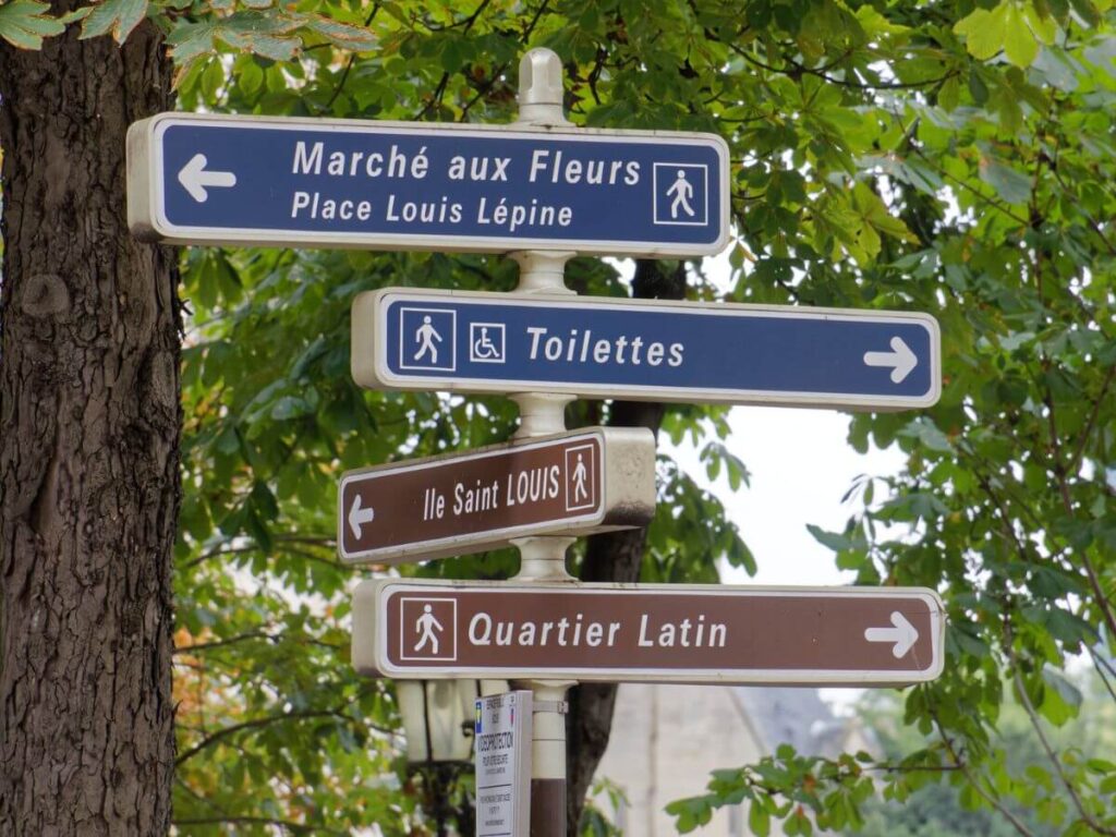 A signpost in Paris showing the way to the Latin Quarter in front of some trees